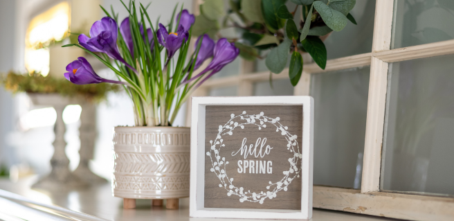 Spring cleaning prep and decor. a vase of purple flowers and a sign that says hello spring